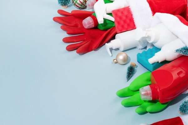 Cleaning tools and Christmas decorations top view flat lay on blue background with copy space